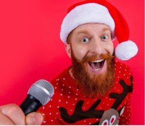 man with christmas hat and beard singing into microphone