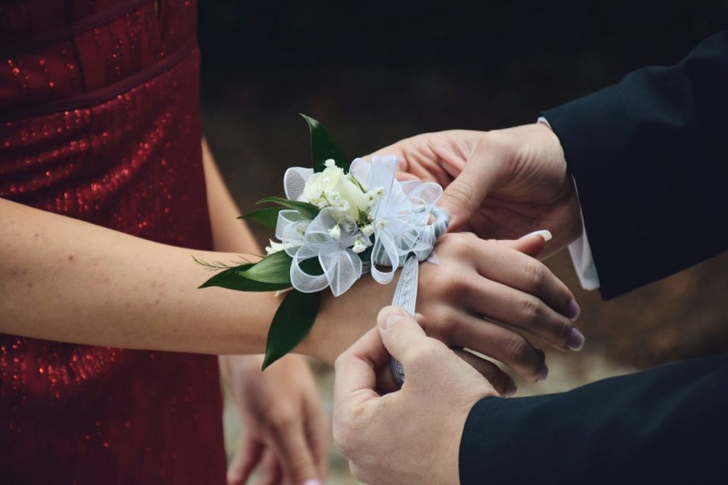 a boy is putting a corsage on girls wrist couples at a special event