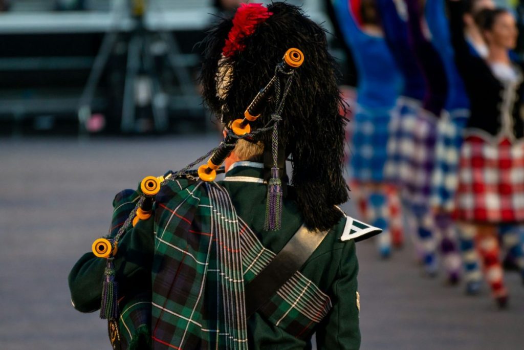 Close up of a man in traditional Scottish attire is playing the traditional Scottish bagpipes
