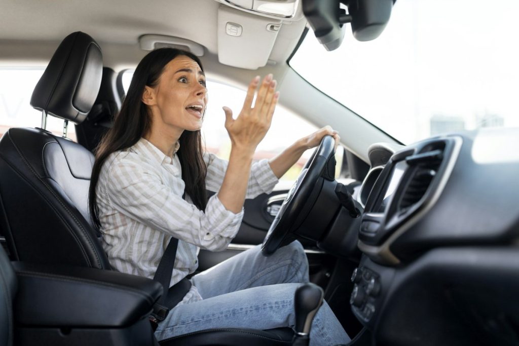 woman driver stuck in traffic jam gesturing with hand screaming