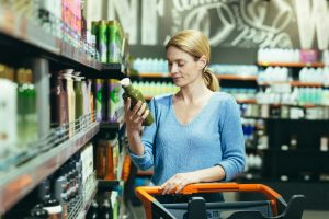 a woman stands in a store in the department of household chemicals with a cart chooses shampoo